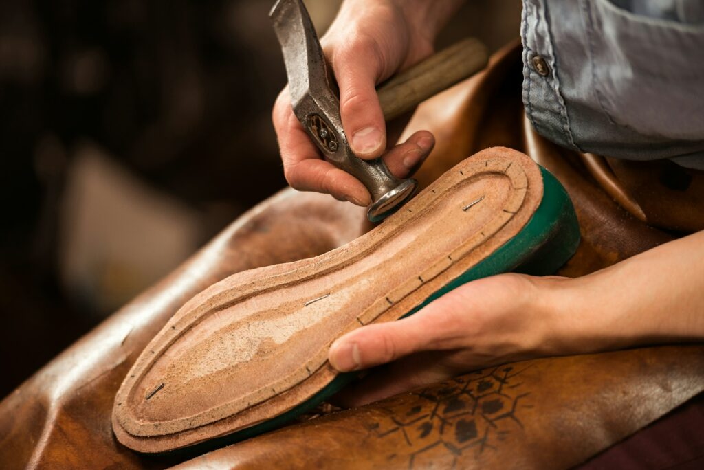 Shoemaker sitting in workshop making shoes
